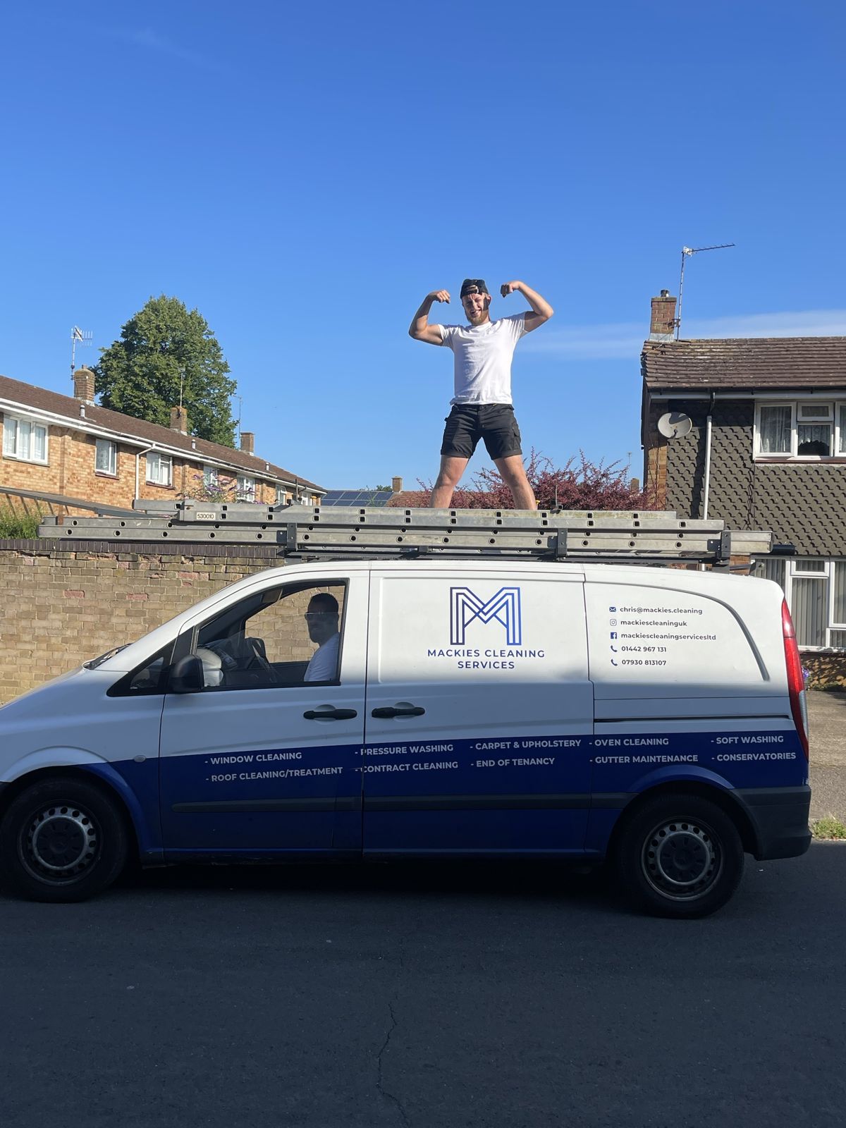 A cleaner standing on the roof of the branded Mackies van, arms up