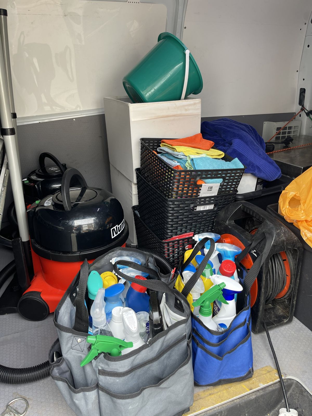 The back of a cleaning van, neatly packed with cloths, caddies and a Numatic hoover