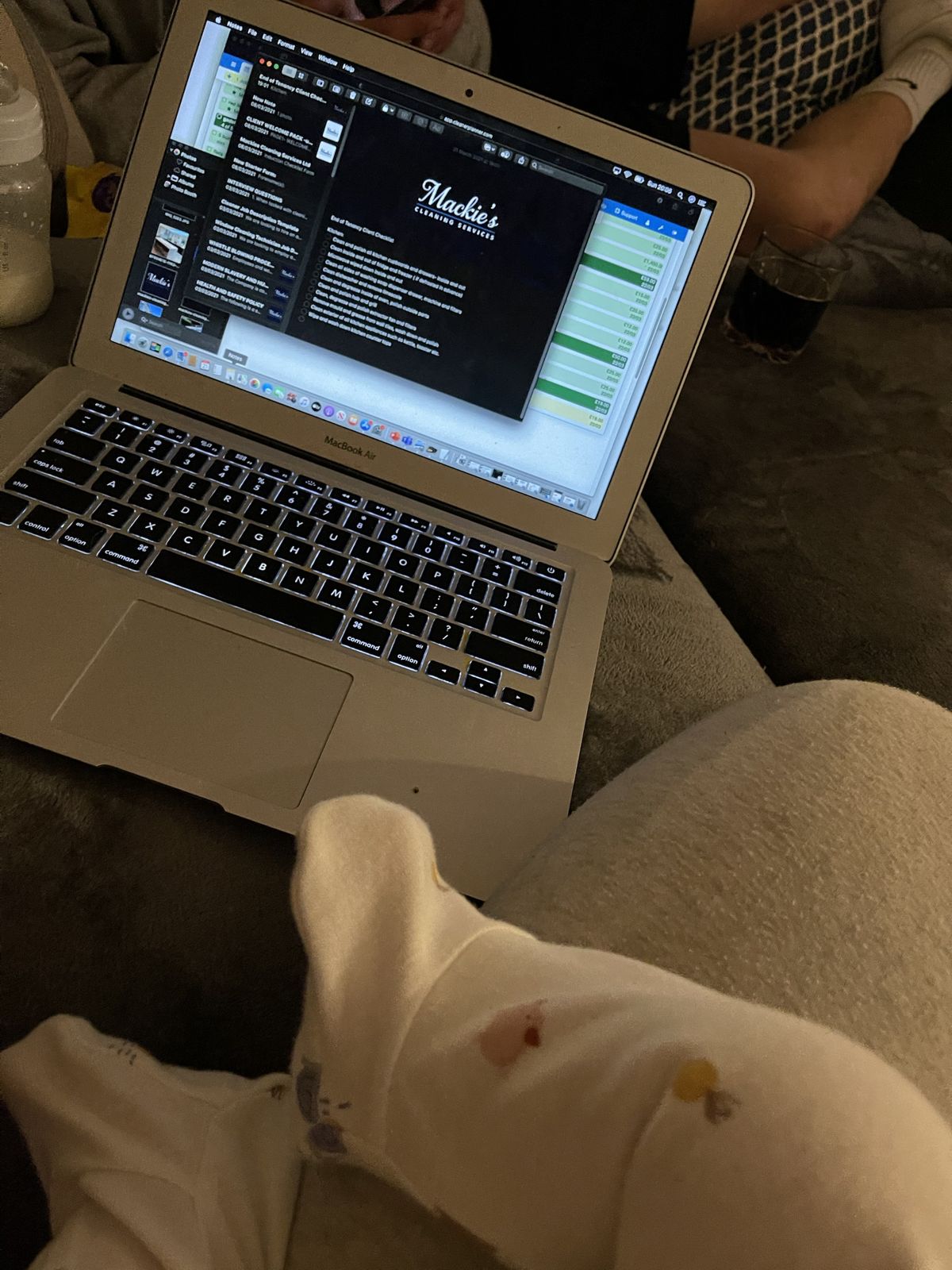 A laptop open on HR templates at the kitchen table, with a baby on a lap in front of it